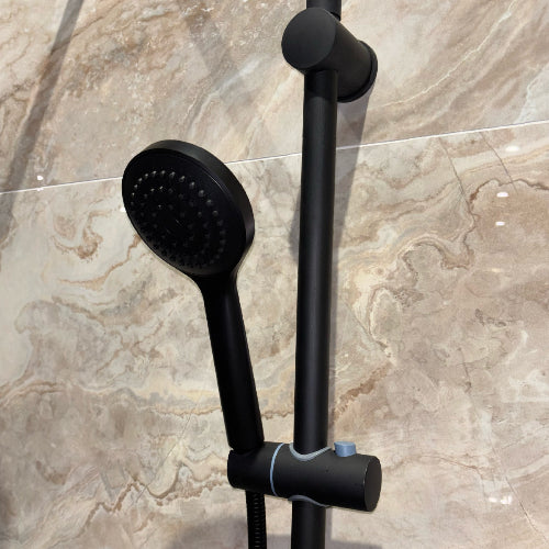 Black shower set with handheld shower head and hose on a tiled wall background