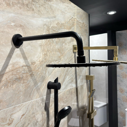 Black and gold shower set mounted on a tiled wall