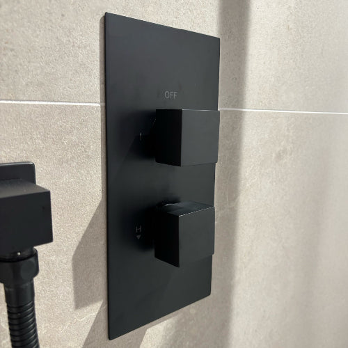 Black shower control panel mounted on a tiled wall
