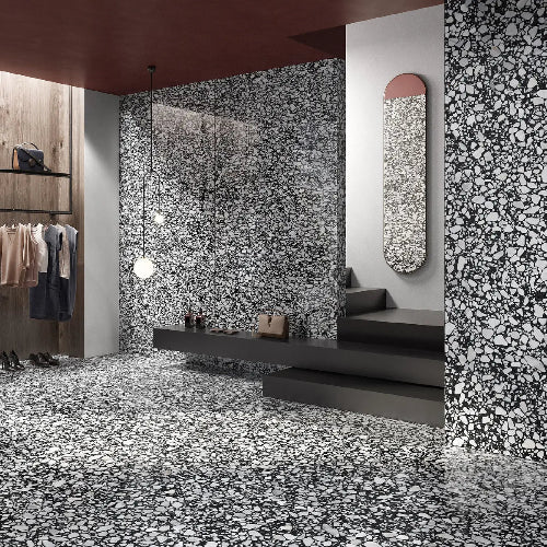 Modern interior with black and white speckled walls and floor, minimal furniture.