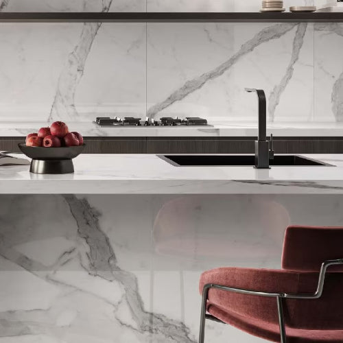 Modern kitchen with marble backsplash, white countertops, and a red chair.