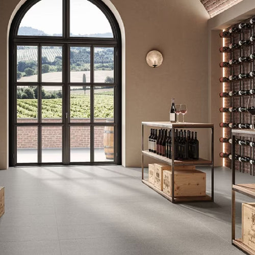 Wine cellar with wine bottles, a display stand, and a large window overlooking vineyards.