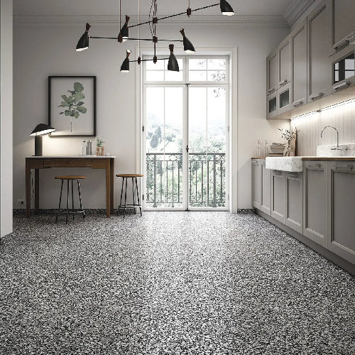 Modern kitchen with gray terrazzo flooring, white cabinets, and a large window.