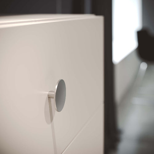 Close-up of a white cabinet with a round metallic handle.