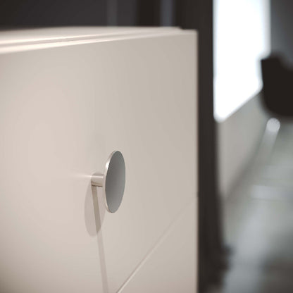 Close-up of a white cabinet with a round metallic handle.