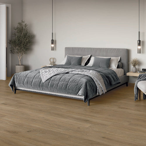 Gray upholstered bed in a modern bedroom with wooden flooring and minimal decor.