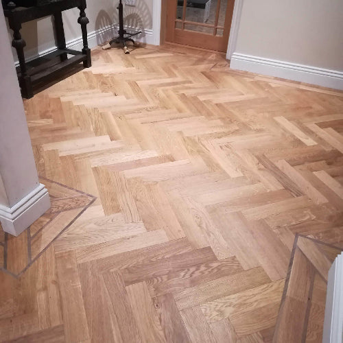 Wooden parquet floor with a herringbone pattern in a room.