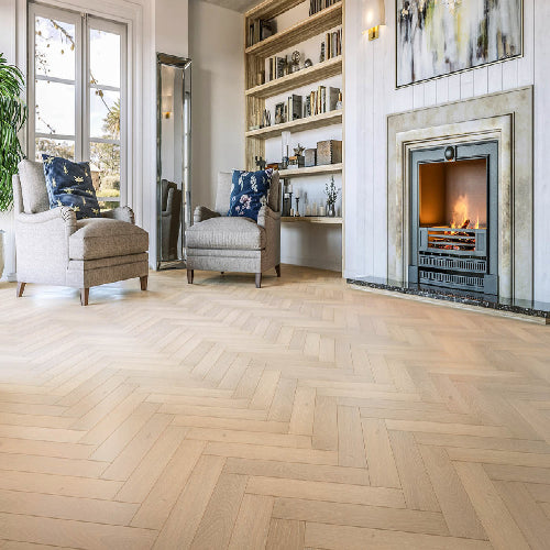 Living room with herringbone wood flooring, fireplace, and bookshelves.
