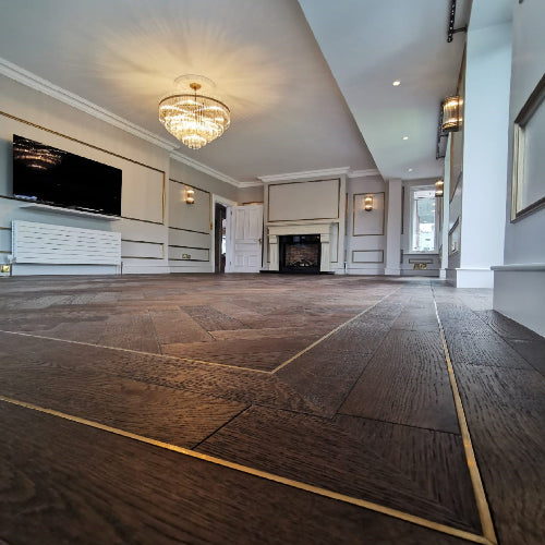 Large room with wooden flooring, chandelier, and wall-mounted TV.