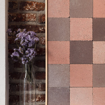 Decorative stone tiles with a vase of purple flowers on a textured wall.