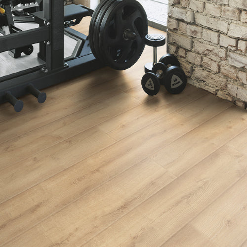 Wooden floor with gym equipment including weights and a treadmill.