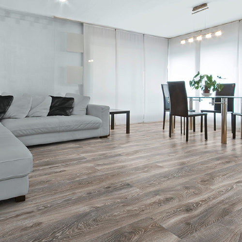 Modern living room with gray sectional sofa, wooden flooring, and a dining area.