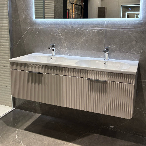 Bathroom vanity with two sinks and a mirror above in a tiled bathroom.