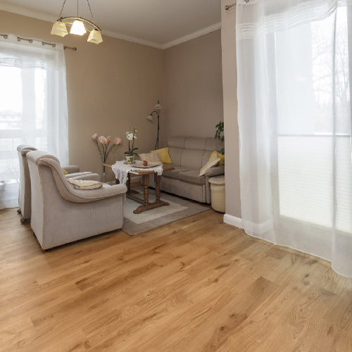 Living room with beige sofa, armchair, and wooden floor.