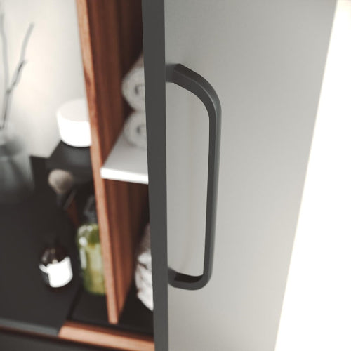 Close-up of a black cabinet handle on a white cabinet with shelves in the background.