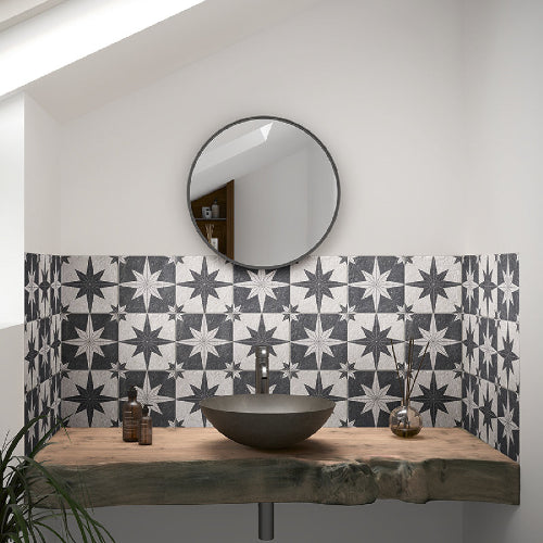 Bathroom with star-patterned tiles, round mirror, and wooden vanity.