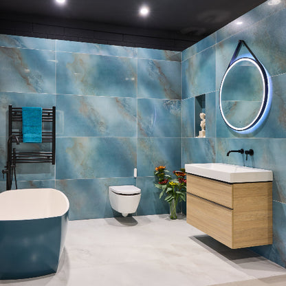 Modern bathroom with blue tiles, wooden vanity, and round mirror.