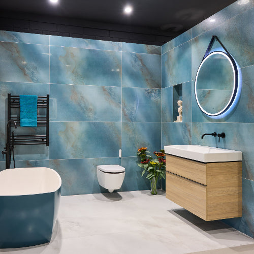 Modern bathroom with blue tiles, wooden vanity, and round mirror.