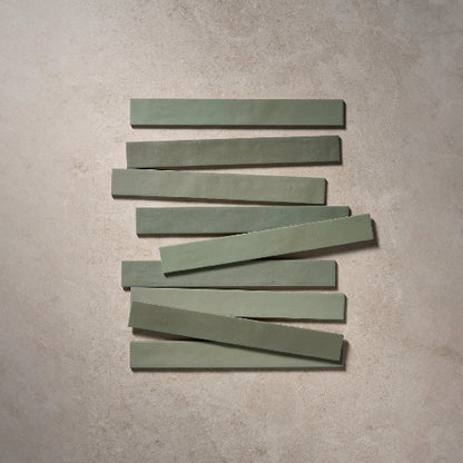 Nine green rectangular tiles arranged in a staggered pattern on a beige surface.
