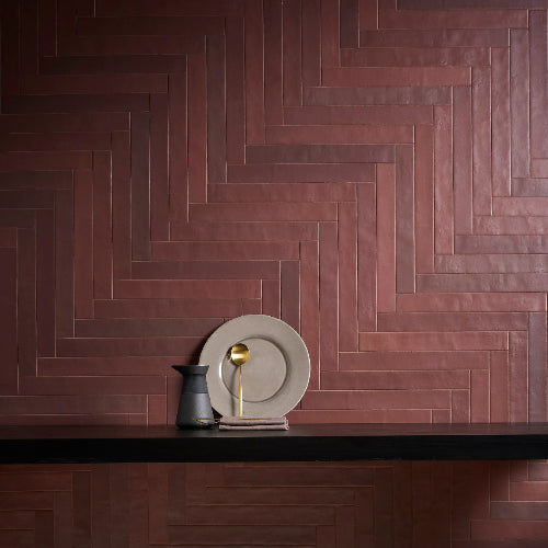 Wooden herringbone pattern on a wall with decorative plates and pitcher.