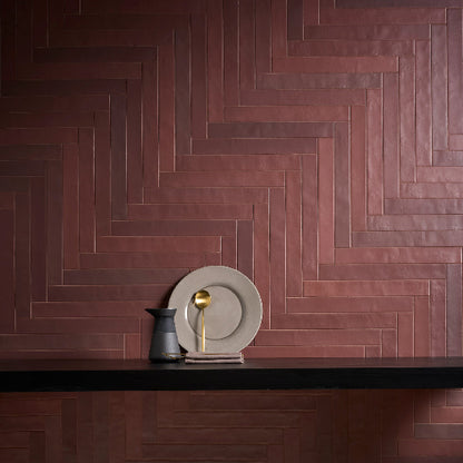 Wooden herringbone pattern on a wall with decorative plates and pitcher.